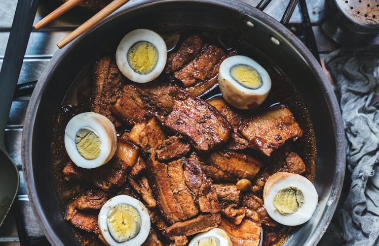 mouthwatering pork adobo with eggs beside the bowl of rice